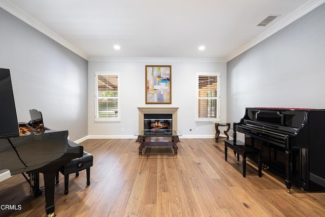 living area with light hardwood / wood-style flooring and ornamental molding