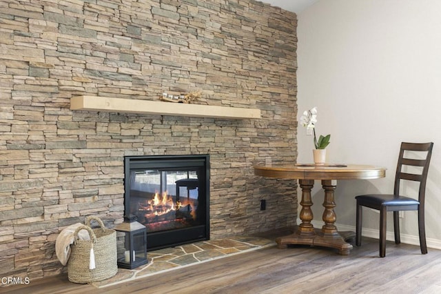 interior details with wood-type flooring and a stone fireplace