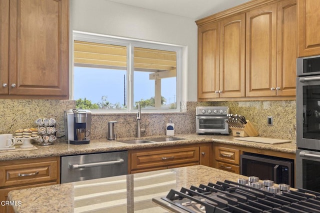 kitchen featuring decorative backsplash, light stone countertops, sink, and appliances with stainless steel finishes