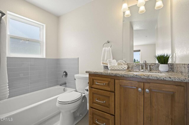 bathroom with a wealth of natural light, a bathtub, vanity, and toilet