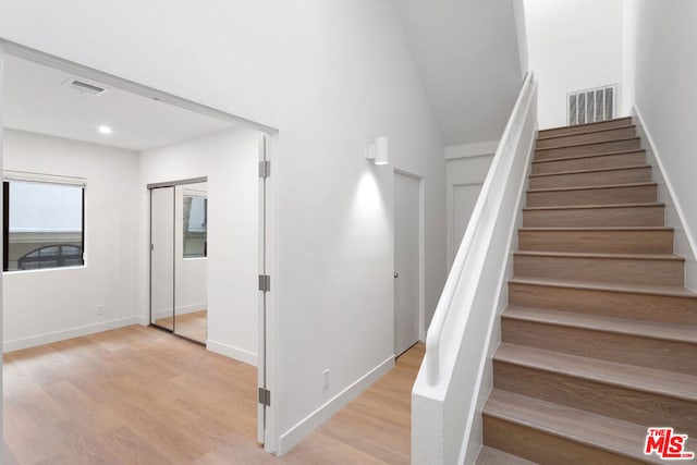 staircase featuring hardwood / wood-style flooring and a towering ceiling