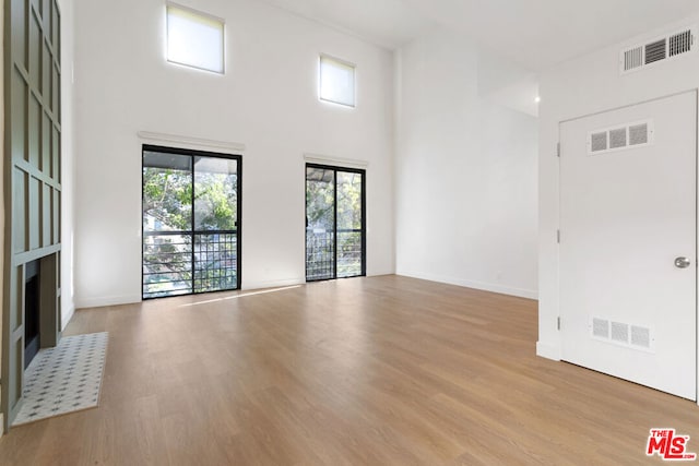 unfurnished living room featuring a towering ceiling and light hardwood / wood-style flooring