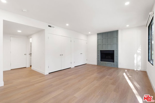 unfurnished living room featuring light hardwood / wood-style floors and a tile fireplace