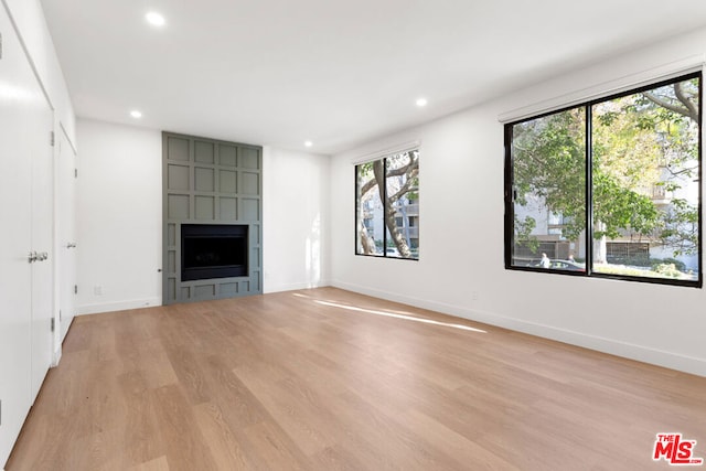 unfurnished living room featuring light wood-type flooring and a large fireplace