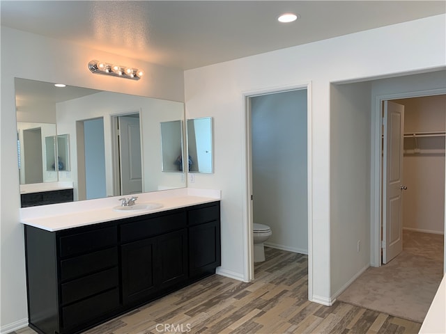 bathroom with hardwood / wood-style flooring, vanity, and toilet