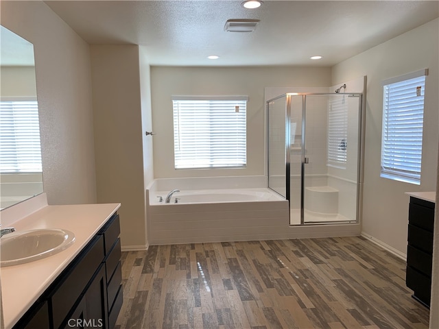 bathroom with hardwood / wood-style flooring, plenty of natural light, vanity, and plus walk in shower