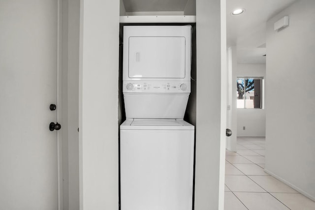 laundry room with stacked washer and dryer and light tile patterned floors