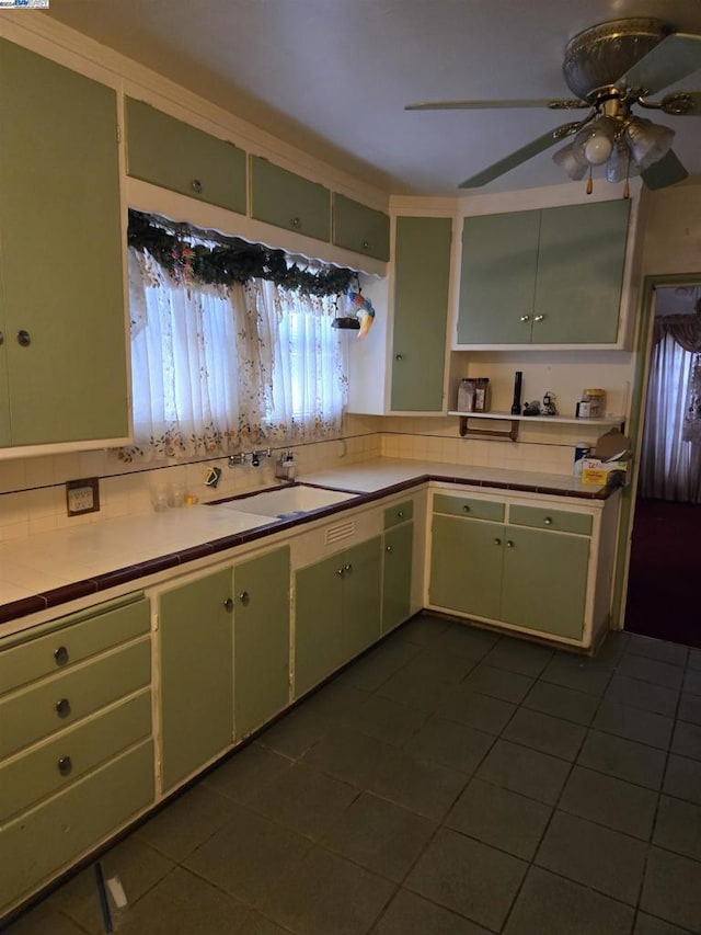 kitchen with green cabinets, ceiling fan, sink, and dark tile patterned flooring