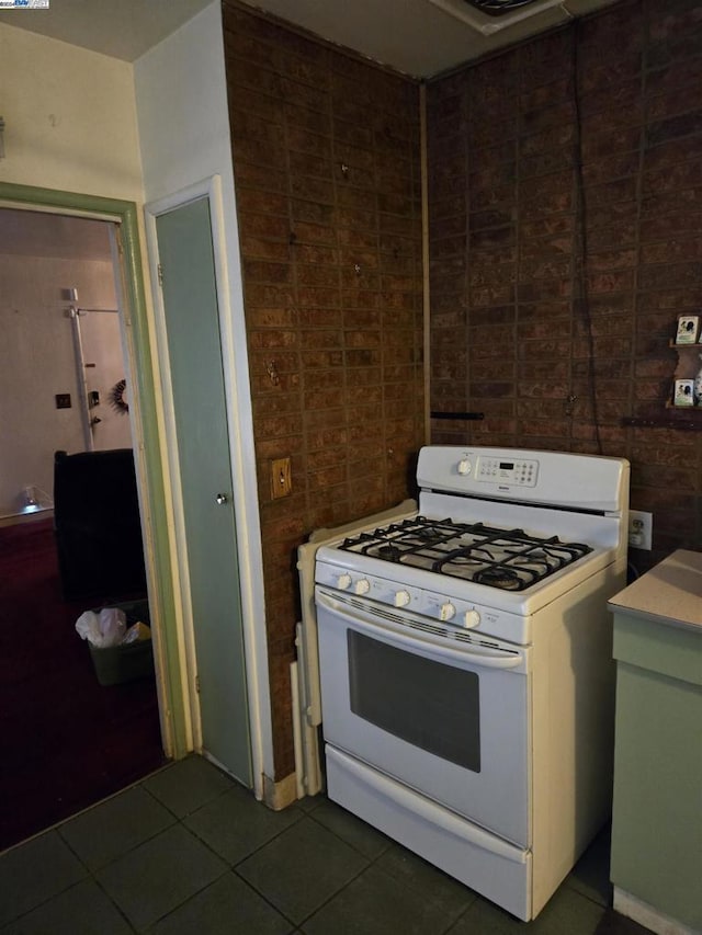 kitchen with white gas range and dark tile patterned flooring