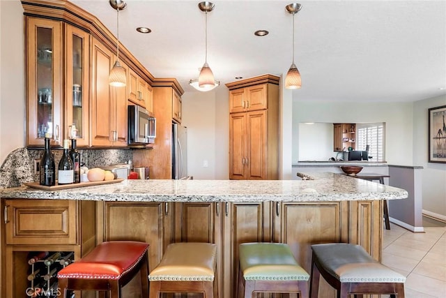 kitchen featuring a kitchen breakfast bar, stainless steel appliances, kitchen peninsula, and light stone counters