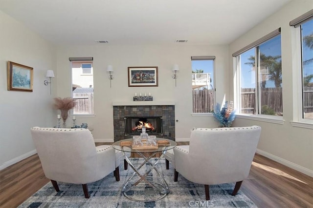 sitting room featuring a fireplace, wood-type flooring, and a healthy amount of sunlight