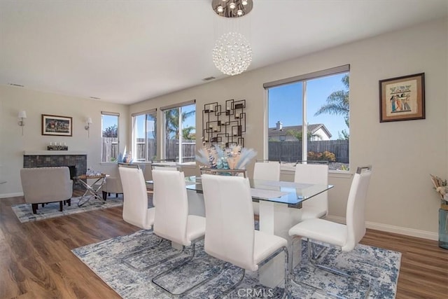 dining room with a tile fireplace, a chandelier, and dark wood-type flooring