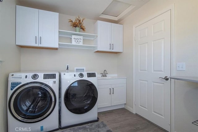 clothes washing area with washer and clothes dryer, dark hardwood / wood-style flooring, cabinets, and sink