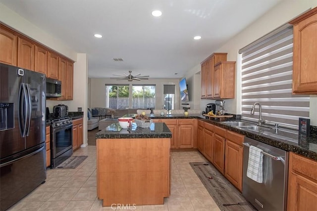 kitchen with a center island, dark stone counters, black appliances, sink, and ceiling fan