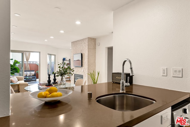 kitchen featuring a fireplace, dishwasher, and sink