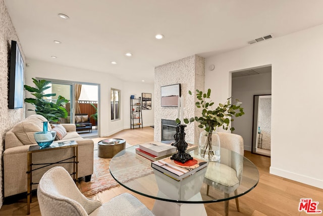 dining area with light wood-type flooring and a large fireplace