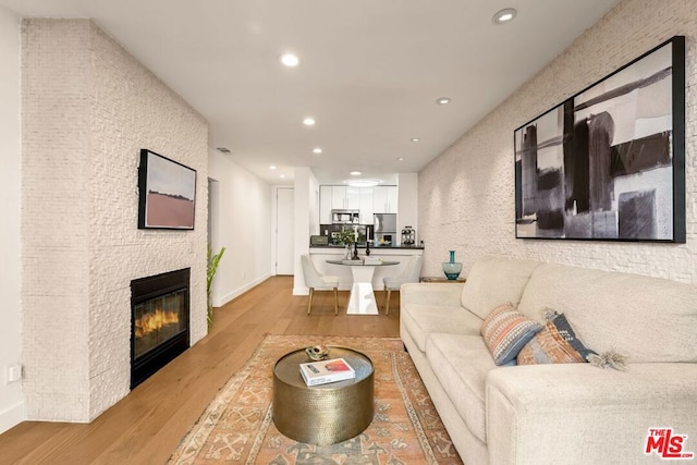 living room featuring a stone fireplace and light hardwood / wood-style flooring