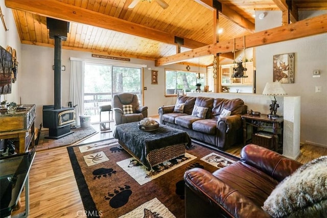 living room with a wood stove, vaulted ceiling with beams, ceiling fan, wood-type flooring, and wood ceiling