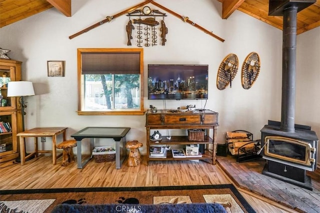 living room featuring hardwood / wood-style floors, vaulted ceiling with beams, and a wood stove