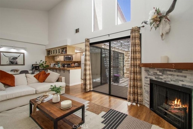 43334 32nd St W Unit 44, Lancaster, CA 93536 - living room featuring a towering ceiling, a fireplace, and light wood finished floors