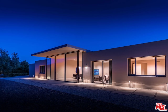 back house at twilight featuring a patio