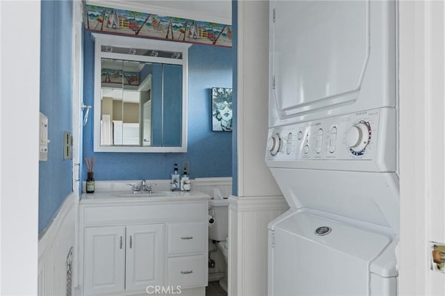 bathroom with vanity, toilet, and stacked washer and clothes dryer