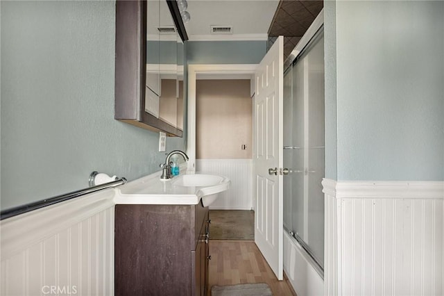 bathroom featuring shower / bath combination with glass door, wood-type flooring, vanity, and crown molding