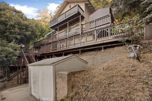 back of property featuring a storage shed and a wooden deck