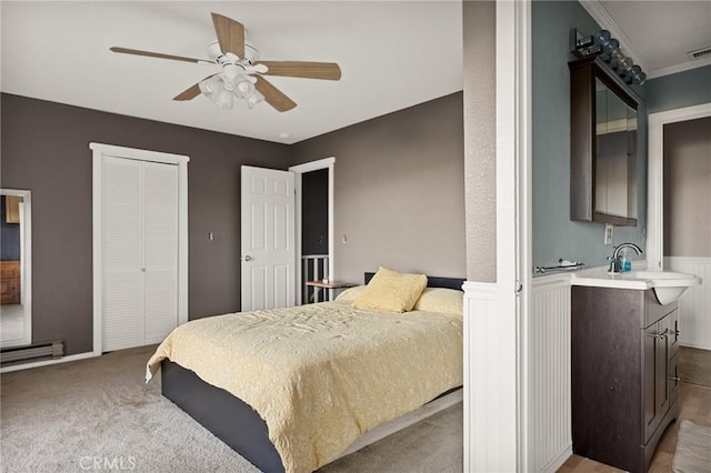 bedroom with ornamental molding, light colored carpet, ceiling fan, sink, and a closet