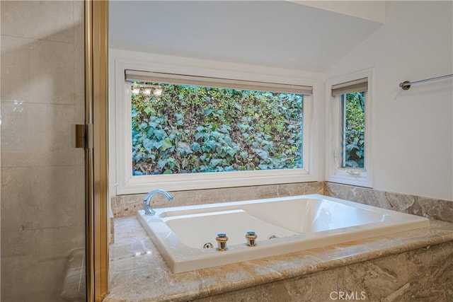 bathroom with vaulted ceiling and a relaxing tiled tub