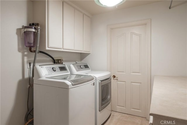 laundry area featuring cabinets, washing machine and dryer, and light tile patterned floors