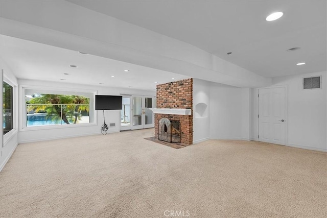 unfurnished living room with light carpet and a brick fireplace