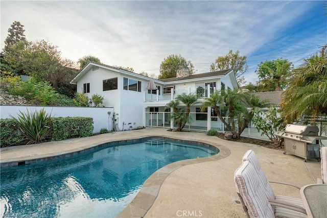 back of house with a balcony, a fenced in pool, and a patio area