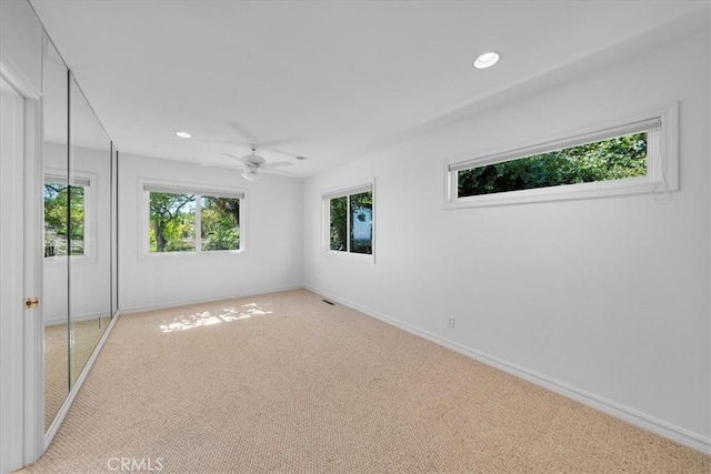 empty room with ceiling fan and light carpet