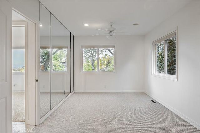 empty room featuring ceiling fan and light carpet