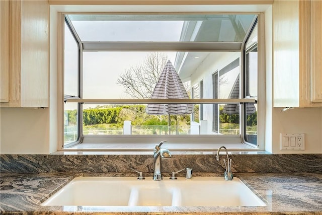 room details with sink, light brown cabinets, and stone counters