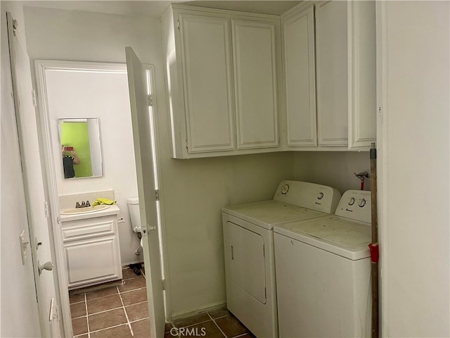 clothes washing area featuring washer and clothes dryer, dark tile patterned flooring, and cabinets