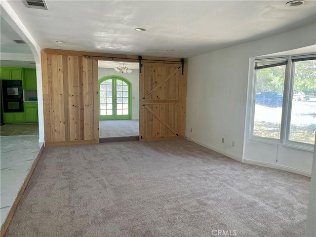 carpeted spare room with a barn door and french doors