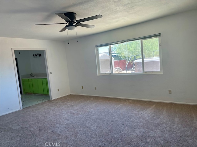 unfurnished room featuring a textured ceiling, ceiling fan, carpet flooring, and sink