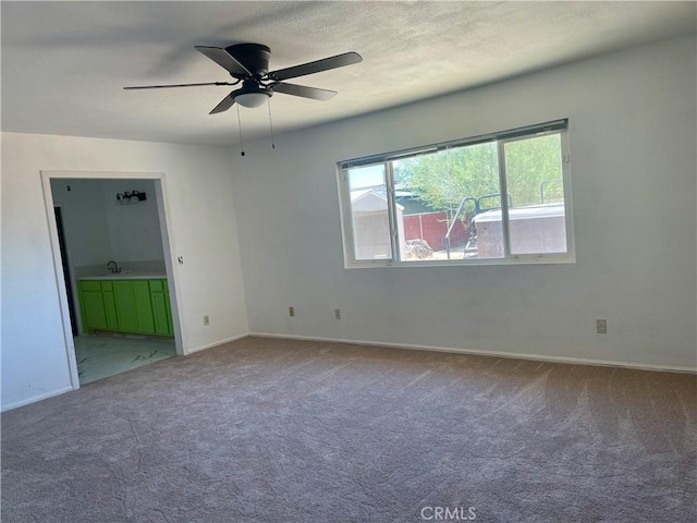 carpeted empty room featuring ceiling fan and sink