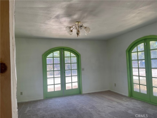 carpeted empty room with french doors, a textured ceiling, and a healthy amount of sunlight