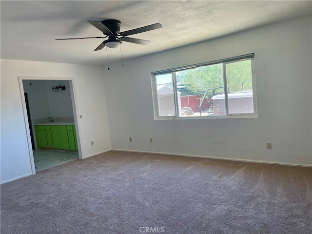 empty room featuring a textured ceiling, ceiling fan, carpet flooring, and sink