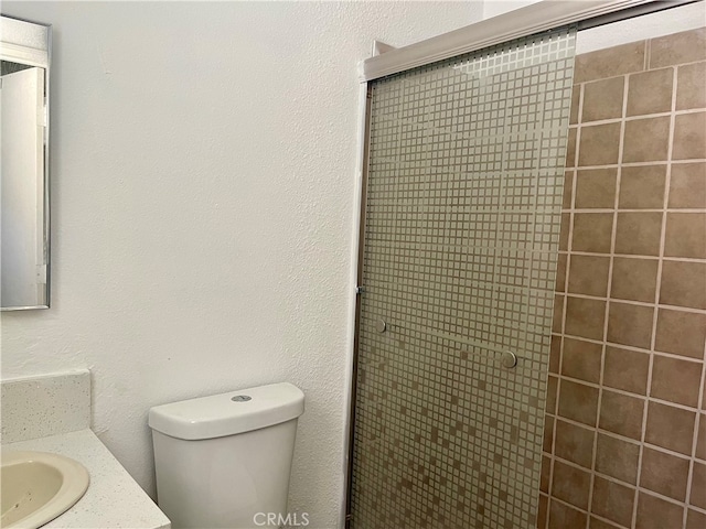 bathroom featuring walk in shower, vanity, and toilet