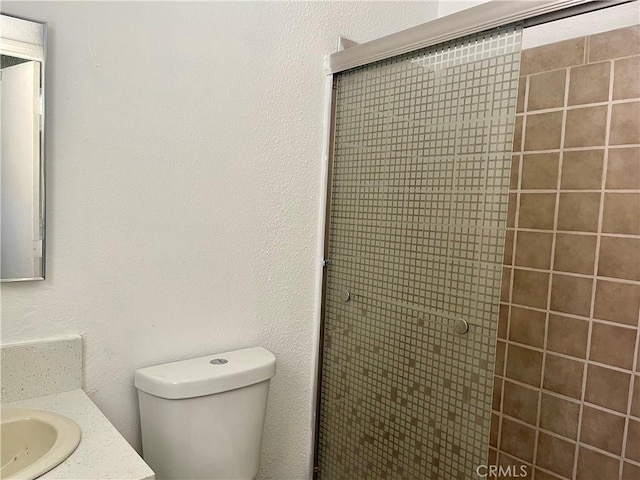 bathroom with toilet, a shower with door, and vanity