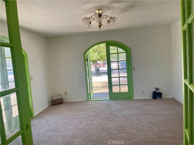 spare room with a chandelier and light colored carpet