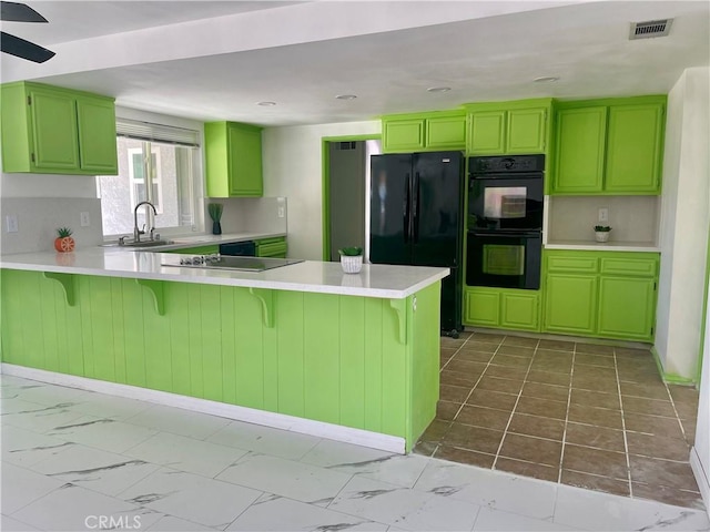 kitchen with green cabinets, black appliances, a breakfast bar area, and kitchen peninsula