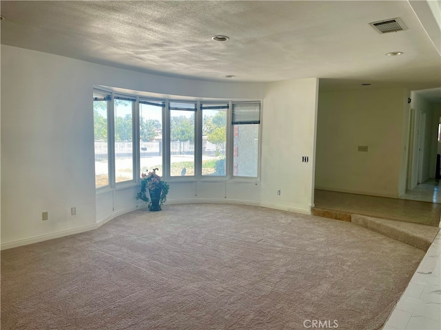 carpeted empty room with a textured ceiling