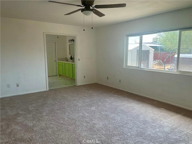 unfurnished room featuring sink, light carpet, and ceiling fan