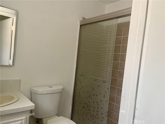 bathroom featuring a tile shower, vanity, and toilet