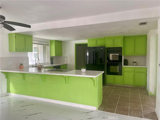 kitchen featuring kitchen peninsula, black appliances, green cabinets, and a kitchen breakfast bar